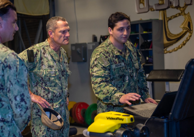 Rear Adm Jeff Jablon left commander of Submarine Force US Pacific Fleet listens as Navy Diver 2nd Class Samuel Adrian right briefs him on dive locker capabilities during a scheduled visit aboard the submarine tender USS Frank Cable AS 40 at Naval Base Guam on May 24 2021 Courtesy of the US Navy