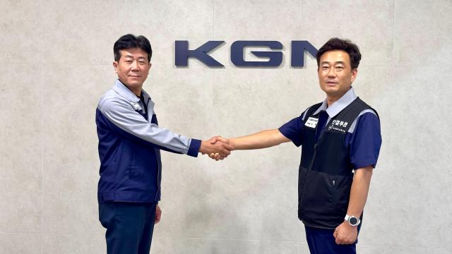 黄基永（左）KGM代表取締役と盧哲労働組合委員長が握手を交わしている