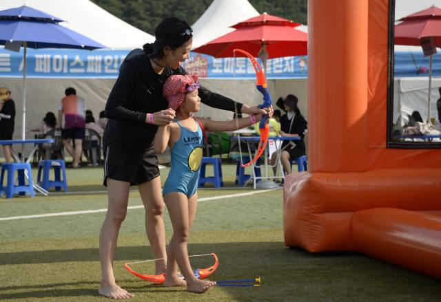 지난 1일 화천군 사내체육공원에서 열린 2026 화천토마토축제에서 물놀이를 즐기던 한 가족이 활쏘기 체험에 참여해 어머니가 아이에게 활 쏘는 방법을 알려주고 있다사진박종석 기자