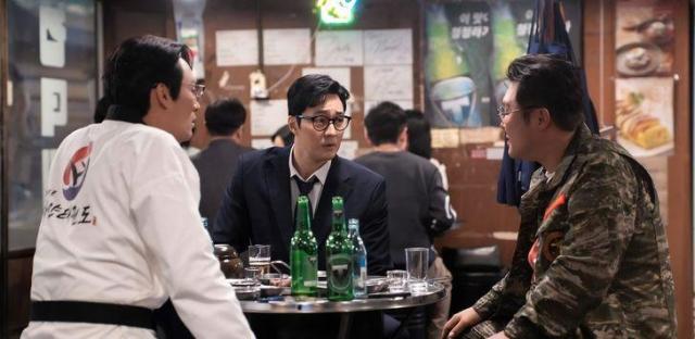 So Ji-subs character sits down with other characters at a table in a scene from Agent kim Reactivated Courtesy of SBS