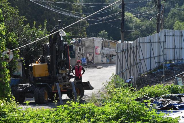 An excavator stands near makeshift homes and overhead power lines at Guryong Village in southern Seoul on Aug 4 2026 AJP Joonha Yoo