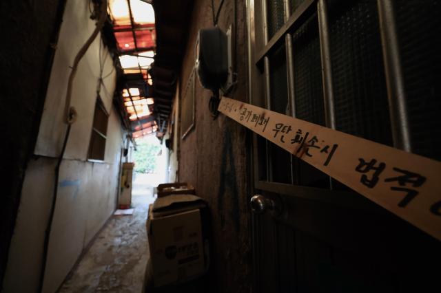 A strip of tape marked with a notice about the closure of a vacant home stretches across a narrow alleyway in Guryong Village Seoul South Korea AJP Han Jun-gu