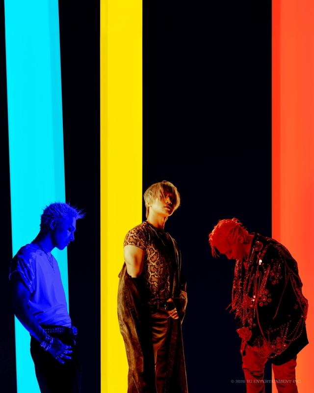 BIGBANG members G-Dragon Taeyang and Daesung pose against blue yellow and red backdrops for the BiiiG release Courtesy of YG Entertainment