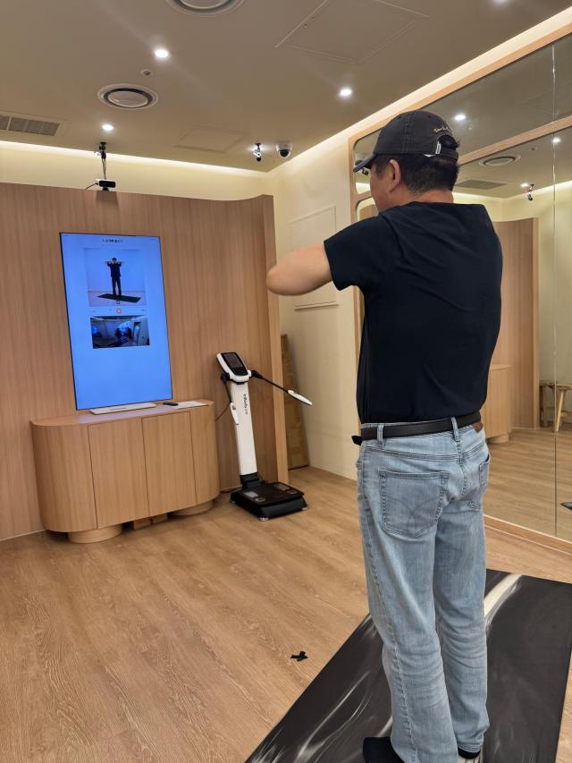 한 체험자가 이 기기 대형 화면의 동작 안내를 따라 움직이며 신체 기능 측정을 체험하고 있다 사진유대길 기자

