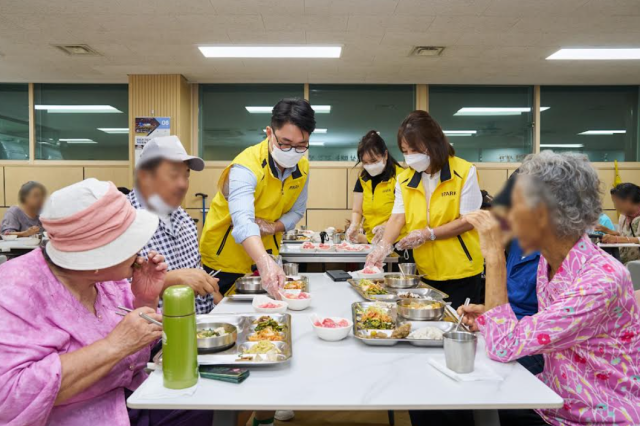 IPARK현대산업개발 직원들이 서울 양천구 신월동에 있는 서서울어르신복지관에서 말복을 맞아 지역 어르신들의 건강한 여름나기를 위한 건강먹거리 기부 및 배식 봉사활동을 진행하고 있다 사진IPARK현대산업개발