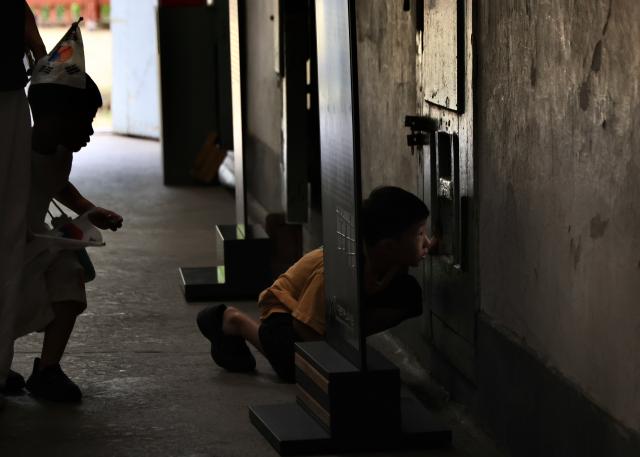 A child peers into a cell through a food slot at Seodaemun prison history hall in Seoul August 14 2026 AJP Han Jun-gu