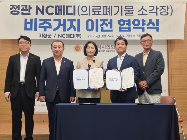우성빈 기장군와 NC메디㈜ 관계자들이 24일 오후 2시 부산시의회 브리핑룸에서 열린 ‘정관 NC메디 의료폐기물 소각시설 비주거지 이전 업무협약식’에서 협약서를 들고 기념촬영을 하고 있다사진박연진 기자