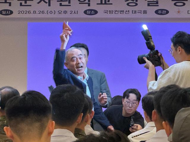 Retired Army Col Oh Sang-bong raises his phone and shouts during a public hearing on the government’s plan to integrate South Korea’s Army Navy and Air Force academies at the Defense Convention in Seoul on Aug 26 2026 AJP Kim Hee-su