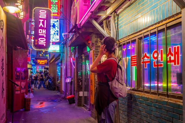 을지로를 찾은 한 여행객이 네온 사진과 인쇄소 간판을 배경으로 사진 촬영을 하고 있다 사진서울관광재단