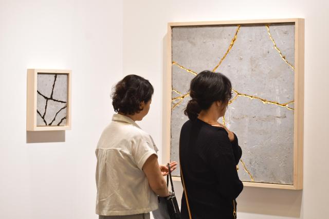 Visitors at Frieze Seoul are staring into an artwork with amazed looks on their faces AJP Joonha Yoo