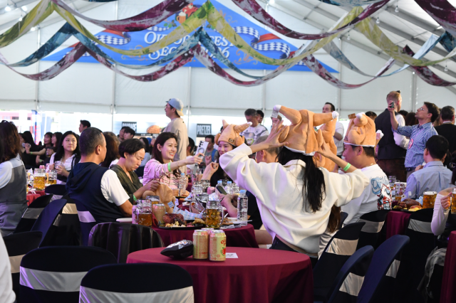 Participants are wearing chicken-shaped novelty hats dance around tables inside the Big Tent during Oktoberfest Seoul 2026 at Oil Tank Culture Park in western Seoul on Sept. 12, 2026. AJP Joonha Yoo