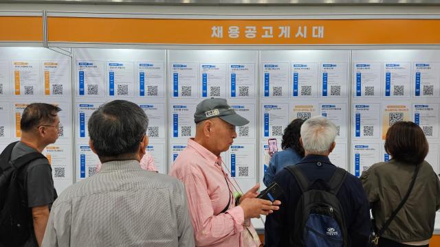 Senior job seekers crowd around a recruitment board displaying job openings during the Seoul Senior Job Fair 2026 at the aT Center in Seocho-gu Seoul Sept 17 2026 The job-posting area drew a steady crowd as visitors compared openings and scanned QR codes for more information AJP Lee Jung-woo