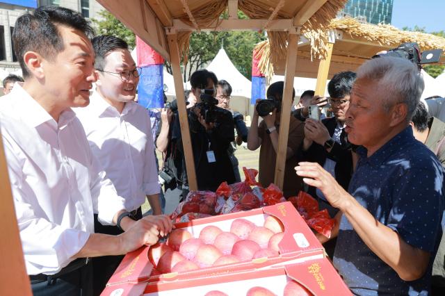 Seoul Mayor Oh Se-hoon and Chungju Mayor Lee Dong-seok talk with a vendor at an apple booth from Chungju during the opening ceremony of the 2026 Chuseok Seoro Market at Seoul Plaza in central Seoul South Korea Sept 15 2026 The direct-to-consumer market organized through cooperation between the Seoul metropolitan government and local governments brings together farmers from across the country and runs through Sept 17 Aju Business Daily Yoo Dae-gil