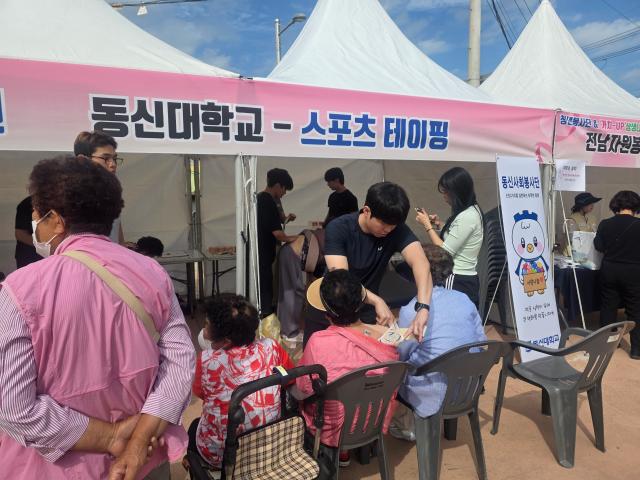18일 무안군 현경면문화복지센터 광장에서 열린 ‘청년봉사단  가치-UP 상생 나눔 프로젝트’에서 동신대학교 학생들이 지역 주민을 대상으로 스포츠테이핑 봉사활동을 펼치고 있다 이날 행사에는 8개 대학과 청년봉사단 유관기관 등이 참여해 17개 통합봉사·체험부스를 운영했다 사진무안군