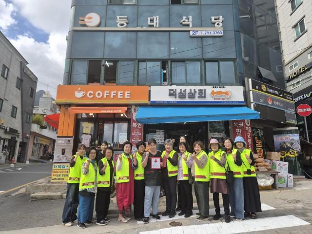 울릉군 사랑의열매 나눔봉사단과 관계자들이 18일 신규 착한가게로 동참한 등대식당을 찾아 현판을 전달한 뒤 기념 촬영을 하고 있다사진울릉군