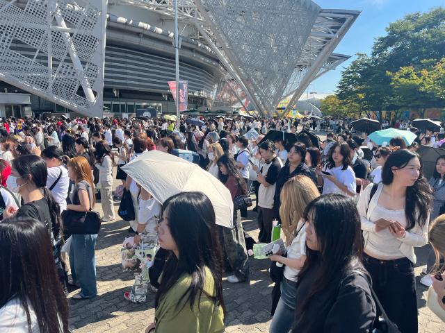 Fans shield themselves from the sun with umbrellas as they gather outside KSPO Dome ahead of an NCT 127 concert AJP Joonha Yoo