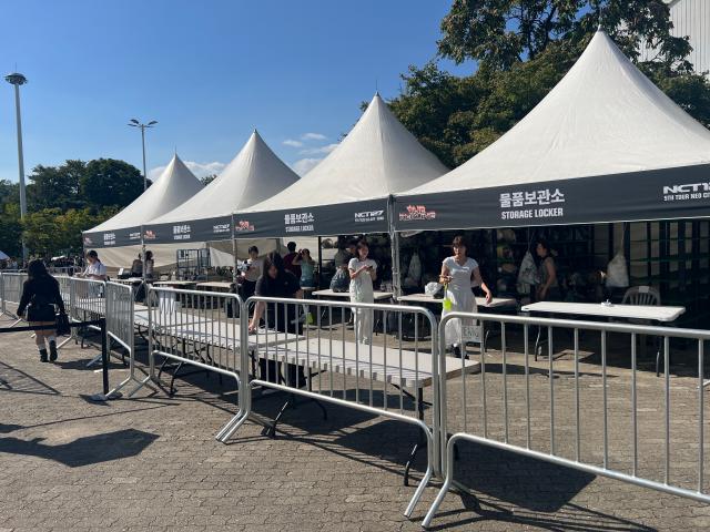 Fans check in bags at a storage locker tent branded for NCT 127s THE REDLINE tour outside KSPO Dome AJP Joonha Yoo