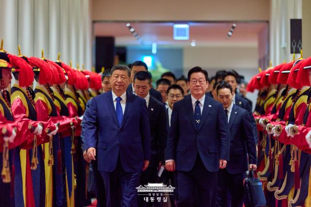 South Korean President Lee Jae Myung right and Chinese President Xi Jinping walk past a traditional honor guard as they arrive for a state dinner in Gyeongju South Korea Nov 1 2025 The dinner was held during Xi’s state visit to South Korea on the sidelines of the APEC summit Courtesy of Cheong Wa Dae