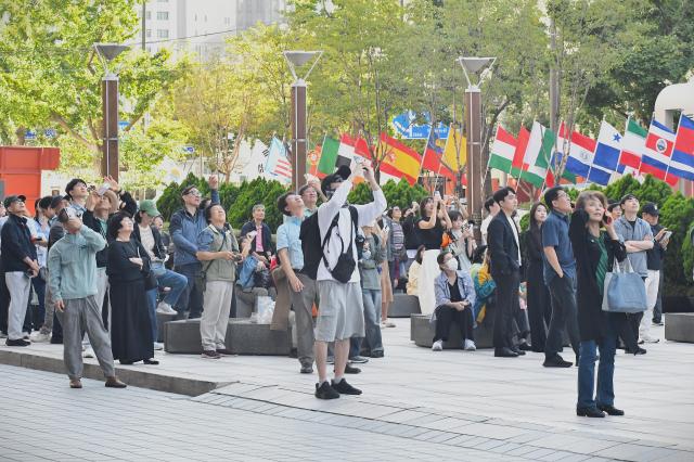 Spectators look up and take photos of Jaan Rooses highline performance in central Seoul on Oct 1 2026 AJP Joonha Yoo