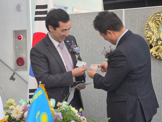 Kazakh Ambassador Asset Issenali left compares his diplomatic ID card with the one he has just presented to Lee Sung-hee right chairman of CONTEC Space Group at the opening ceremony of the Honorary Consulate of the Republic of Kazakhstan at CONTEC in Daejeon Oct 2 2026 AJP Park Sae-jin