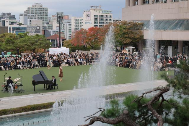 An overview of Miss Gee Collections 2027 springsummer fashion show at the outdoor Music Plaza of the Seoul Arts Center in southern Seoul on Oct 15 2026 with models walking the runway beside the World Music Fountain as guests watch Aju Business Daily Yoo Dae-gil