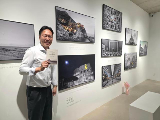 Nam Joo-cheol a co-host of the English-learning program Easy English on the Korea Educational Broadcasting System poses in the space displaying his smartphone travel photographs at “Memory for Tomorrow” a youth art exhibition held at The Star Gallery in Seoul’s Insadong from Sept 30 to Oct 5 Courtesy of Sally Mom Art