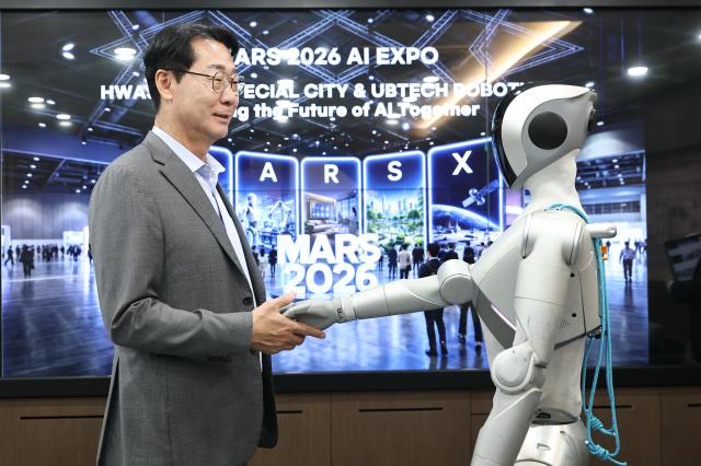 정명근 화성특례시장이 「MARS 2026」 개막식 오프닝 무대에서 발레 퍼포먼스를 선보일 로봇 ‘루나LUNA’와 악수를 하고 있다 사진화성시