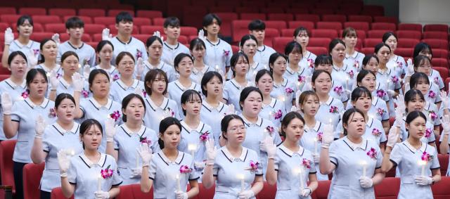 경남정보대학교 치위생과 3학년 재학생들이 _제22회 KIT 치과위생사 선서식 및 학술제_에서 촛불을 들고 선서하고 있다사진경남정보대