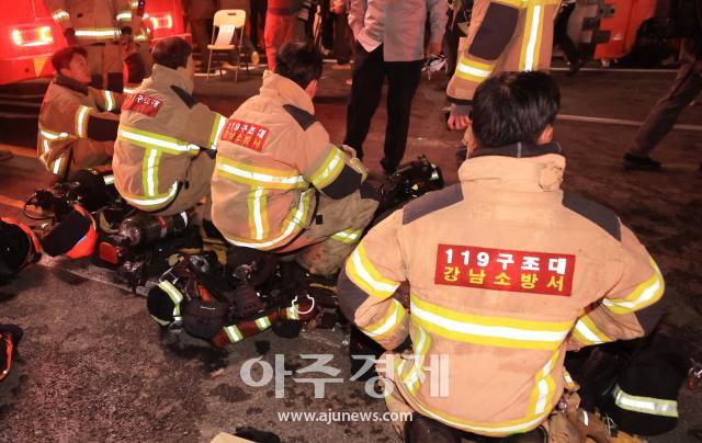 Bomberos descansando brevemente durante operaciones en Gangnam, Seúl