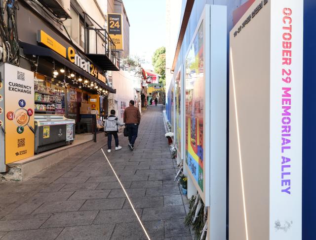 Pedestrians walk through the narrow sloping alley where the 2022 Itaewon crowd crush occurred in Seouls Yongsan District on October 28 2026 a day before the fourth anniversary of the disaster Memorial panels and flowers line the passage AJP Yoo Na-hyun 