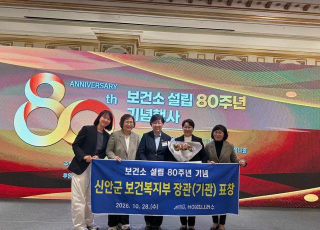 신안군보건소 관계자들이 28일 열린 ‘보건소 설립 80주년 기념행사’에서 도서지역 공공보건의료 발전과 주민 건강증진에 기여한 공로로 보건복지부 장관 기관표창을 수상한 뒤 꽃다발과 축하 현수막을 들고 기념촬영을 하고 있다 사진신안군
