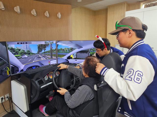 충남도립대학교 작업치료학과 학생들이 지난 27일 대학 진리관 실습실에서 청양지역 어르신들의 인지활동과 운전 시뮬레이션 체험을 돕고 있다사진